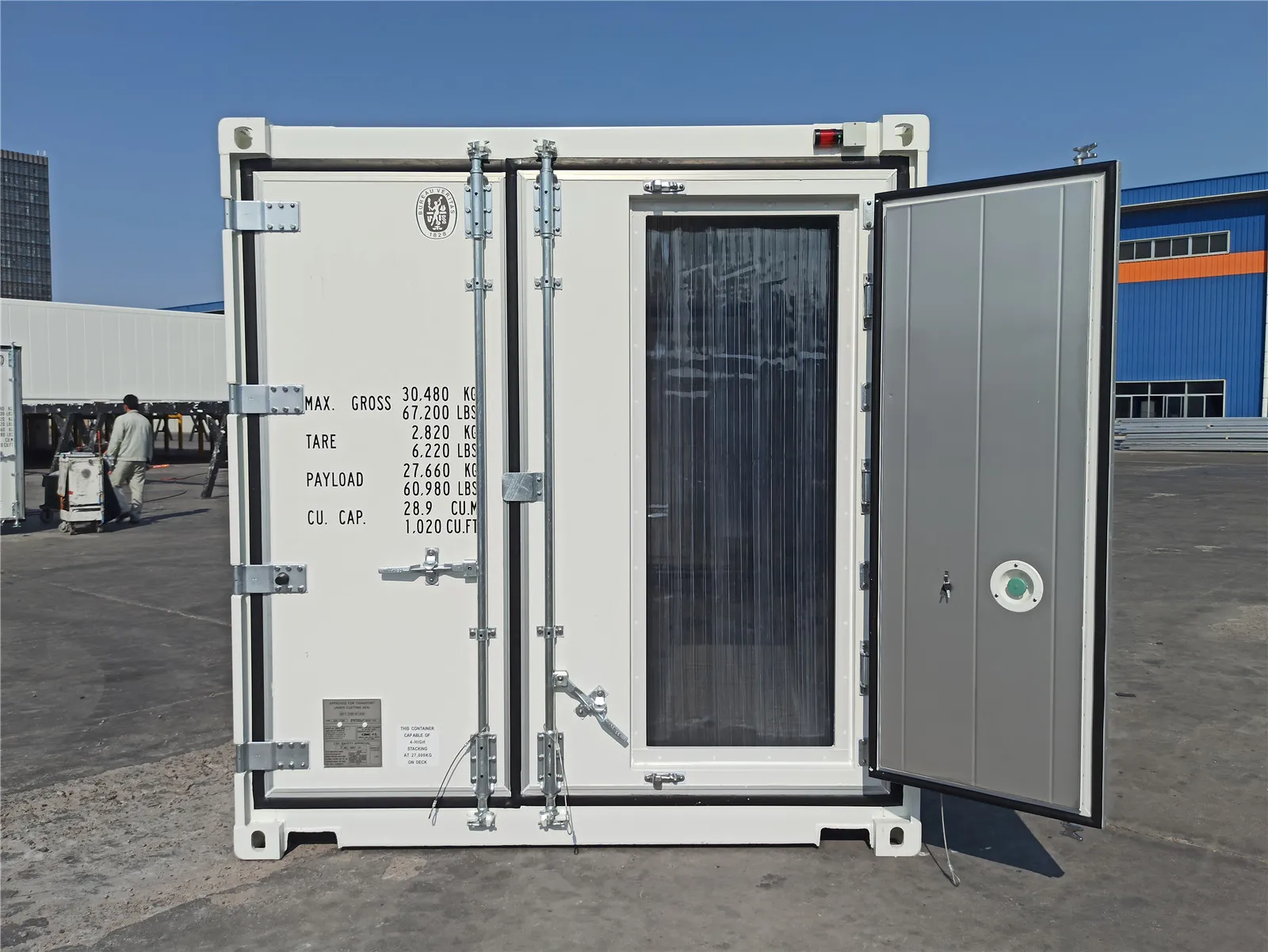 Weißer 20-Fuß-Kühlcontainer mit geöffneter Tür und Lamellenvorhang, Stirnseite im Depot.