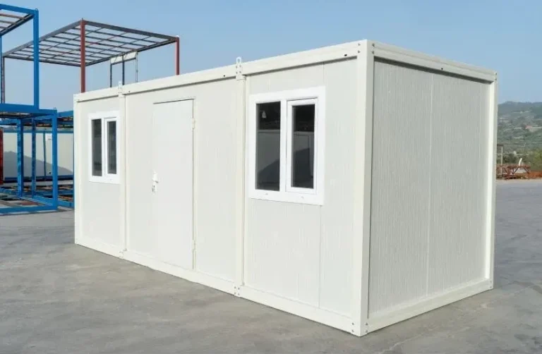 Bürocontainer in Schrägansicht mit Eingangstür und Fenstern, auf Betonfläche im Depot.