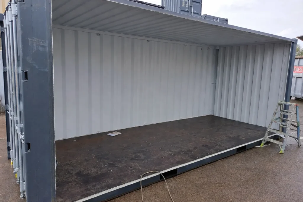 Container mit großem Seitendurchbruch – Blick in den Innenraum mit geöffnetem Wandbereich und Leiter im Hintergrund.