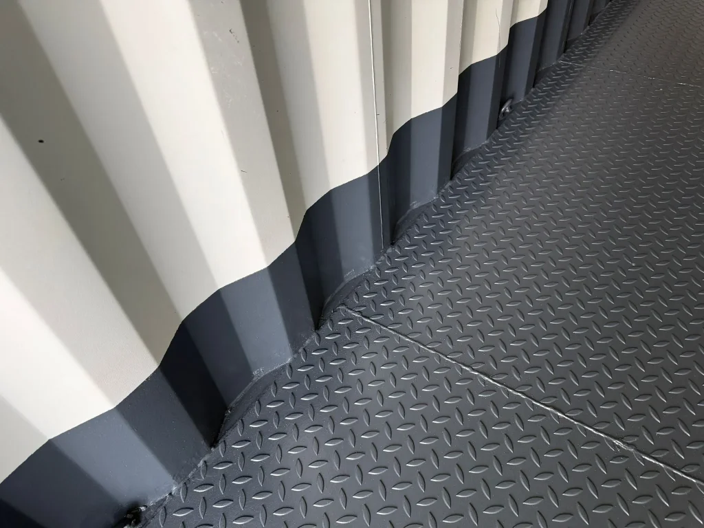 Detail: Stahl-Riffelblechboden im Container mit sauberem Randabschluss entlang der Seitenwand.